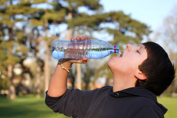 Un garçon assoiffé d'eau potable de bouteille en plastique — Photo
