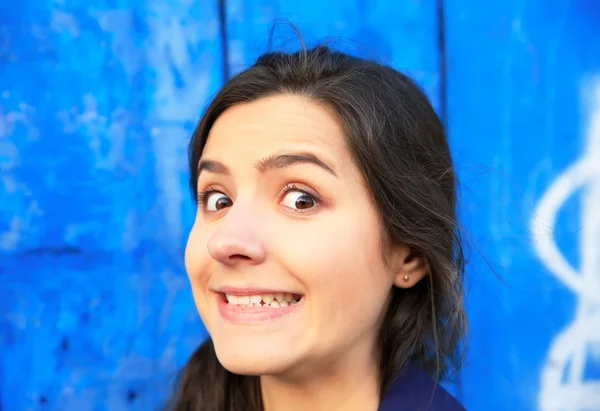 Uma bela jovem mulher surpreso no fundo da parede azul — Fotografia de Stock