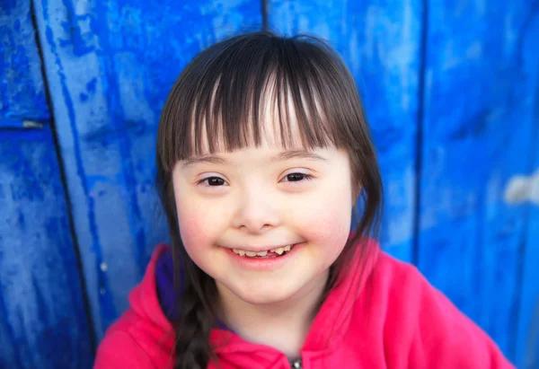 Νεαρό κορίτσι χαμογελά σε φόντο μπλε τοίχο — Φωτογραφία Αρχείου