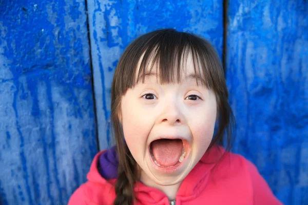 Молодая девушка улыбается на фоне синей стены — стоковое фото