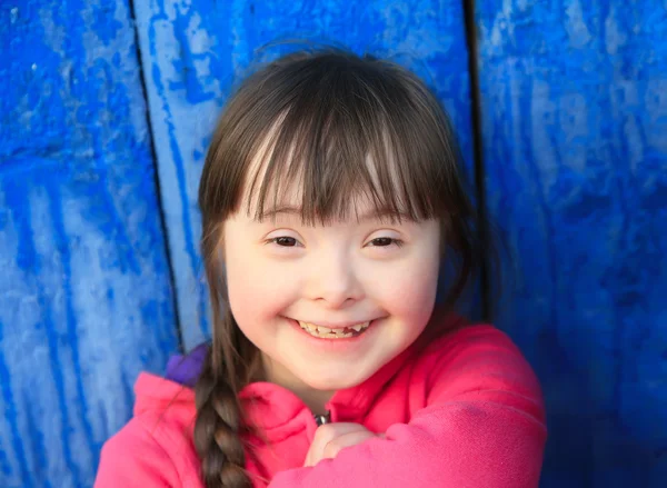 Menina sorrindo no fundo da parede azul — Fotografia de Stock