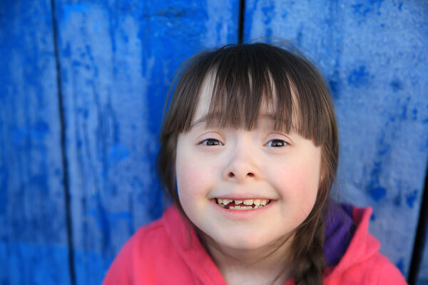 Молодая девушка улыбается на фоне синей стены

