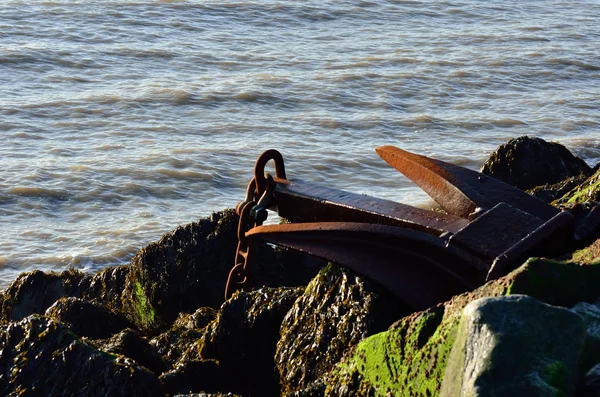 Large rusty anchor on top of group of rocks — Stock Photo, Image