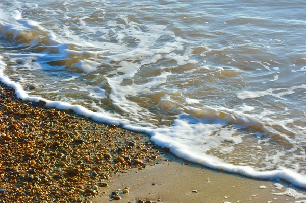 Vågor och singel på strandlinjen — Stockfoto