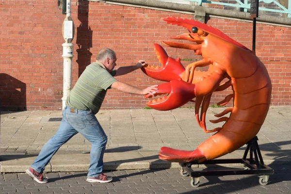 Homem empurrando lagosta de plástico lifesize — Fotografia de Stock