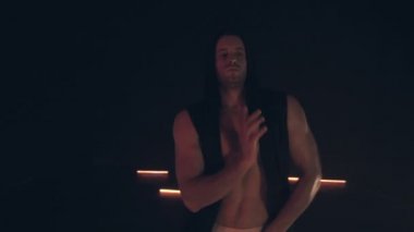 Maskeli seksi adam karanlıkta dans ediyor.