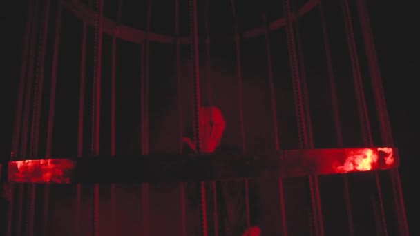 Mannen i svart i rött ljus i rök nära metallburen — Stockvideo