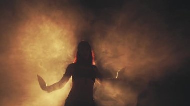 Woman dancing in smoke on a dark background