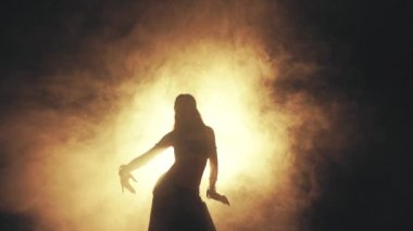 Woman dancing in smoke on a dark background