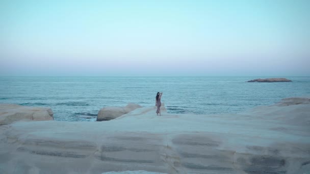 Μια γυναίκα περπατά κατά μήκος της ακτής πάνω στα βράχια — Αρχείο Βίντεο