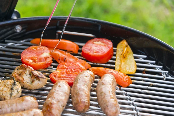 Saucisses, viande et légumes sur un gril — Photo