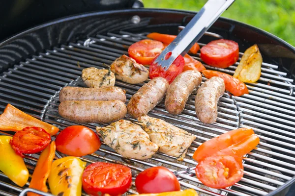 Saucisses, viande et légumes sur un gril — Photo