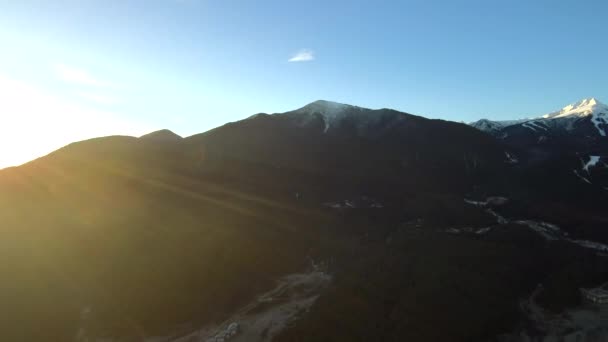 지평선에 눈덮인 산들이 있는 화창 한 아침에 그 마을 위에 떠 있는 공중 장면 — 비디오