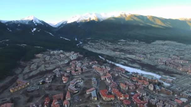 Luchtbeelden boven het dorp op een zonnige ochtend met besneeuwde bergen aan de horizon — Stockvideo