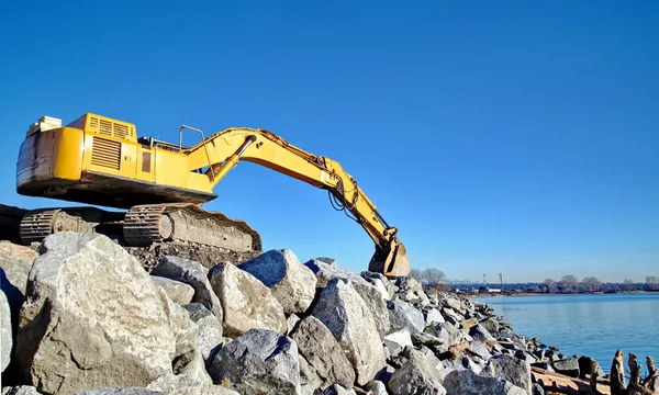 Bagger auf großen Felsen am Strand — Stockfoto