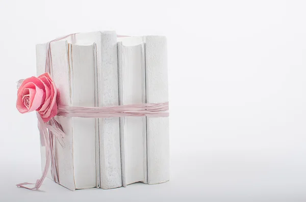 Stapel boeken gerelateerde boog met roos op een witte achtergrond Stockafbeelding