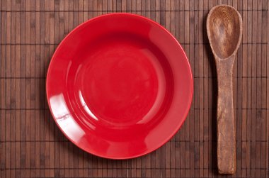 Masada kırmızı tabak ve tahta kaşık..