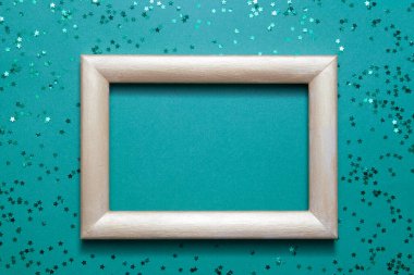 Boş fotoğraf çerçevesi, yeşil kağıttan arka planda birçok yeşil parlak yıldızla modellenir: tatil kavramı