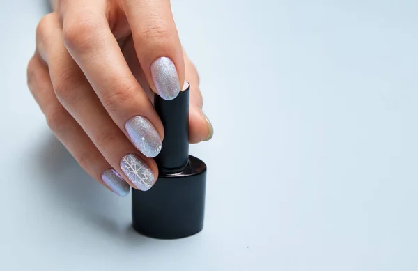 Mão feminina com manicure de inverno e uma garrafa de esmalte com espaço de cópia — Fotografia de Stock