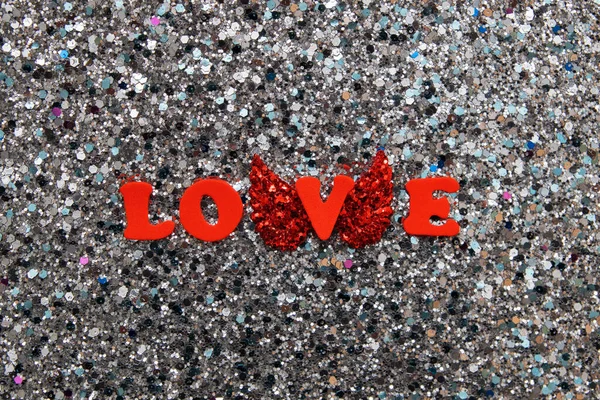 Η λέξη Αγάπη με κόκκινα γράμματα με φτερά σε λαμπερό φόντο γκλίτερ για την Ημέρα του Αγίου Βαλεντίνου — Φωτογραφία Αρχείου