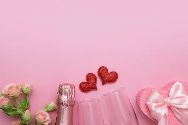 Widok z góry dwa czerwone serca, okulary, szampan, kwiaty na różowym tle z miejsca ksero Walentynki daty lub koncepcji partii — Zdjęcie stockowe