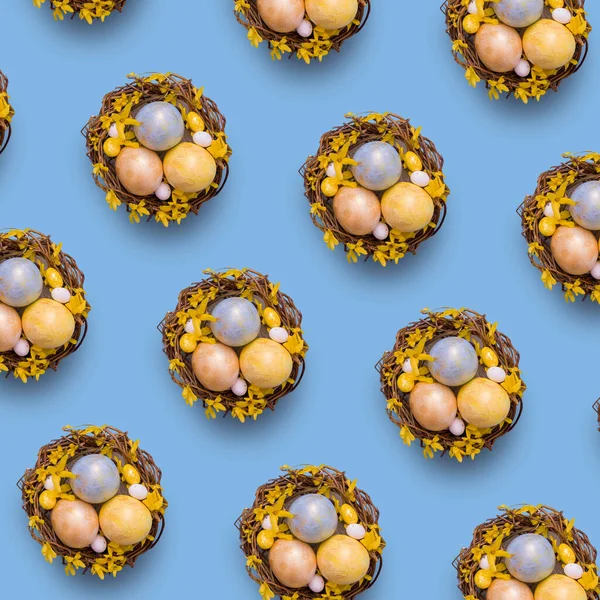 Top view Gniazdo z kolorowymi jajkami z kwiatami na niebieskim tle. Skopiuj miejsce na tekst wielkanocny — Zdjęcie stockowe