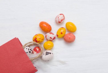 Boyanmış beyaz ahşap arka planda farklı renklerde bir paket çikolata paskalya yumurtası.