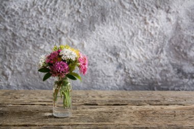 Ahşap masada çiçekli minyatür cam şişe ve fotokopi alanı olan güneş ışığı ile beton zemin