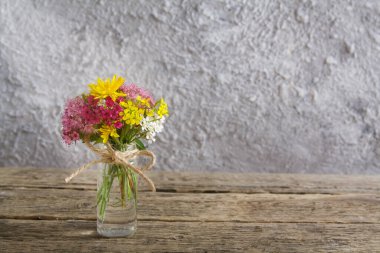 Ahşap masada çiçekli minyatür cam şişe ve fotokopi alanı olan güneş ışığı ile beton zemin