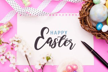 Paskalya tatilin kutlu olsun. Kağıt üzerinde paskalya yuvası ve renkli fırında çiçek açan dallı yumurtalar.