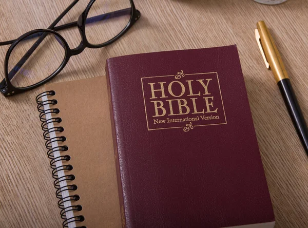 Sacra Bibbia, quaderno, bicchieri e penna su una scrivania — Foto Stock