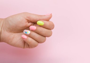 Yazın manikürlü, pembe arka planda dondurmalı kadın eli.