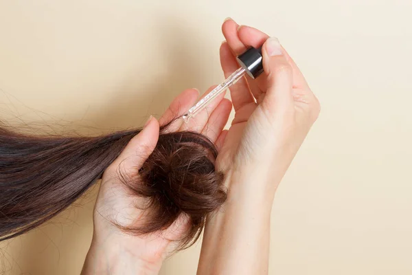 Tangan wanita mengaplikasikan agen komedi ke ujung rambut dengan pipet. Konsep perawatan rambut — Stok Foto