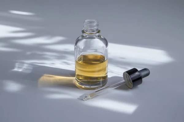 Open glazen druppelflesje met huidverzorging cosmetisch. Boter, serum of tinctuur met harde schaduw Stockfoto
