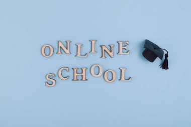 Text from wooden letters School online and graduate cap on blue background