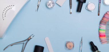 Tools and materials for manicure flat lay with copy space in banner format. Knolling on a blue background
