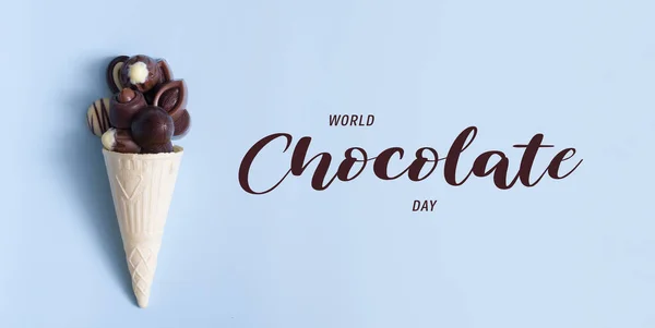 Banner witn text World Chocolate Day and chocolate pralines in waffle cone on blue background