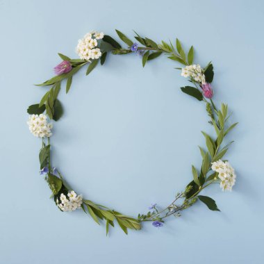 Mavi arka planda fotokopi alanı olan yuvarlak bir çerçeve. Yaz ya da bahar çiçekli arka plan