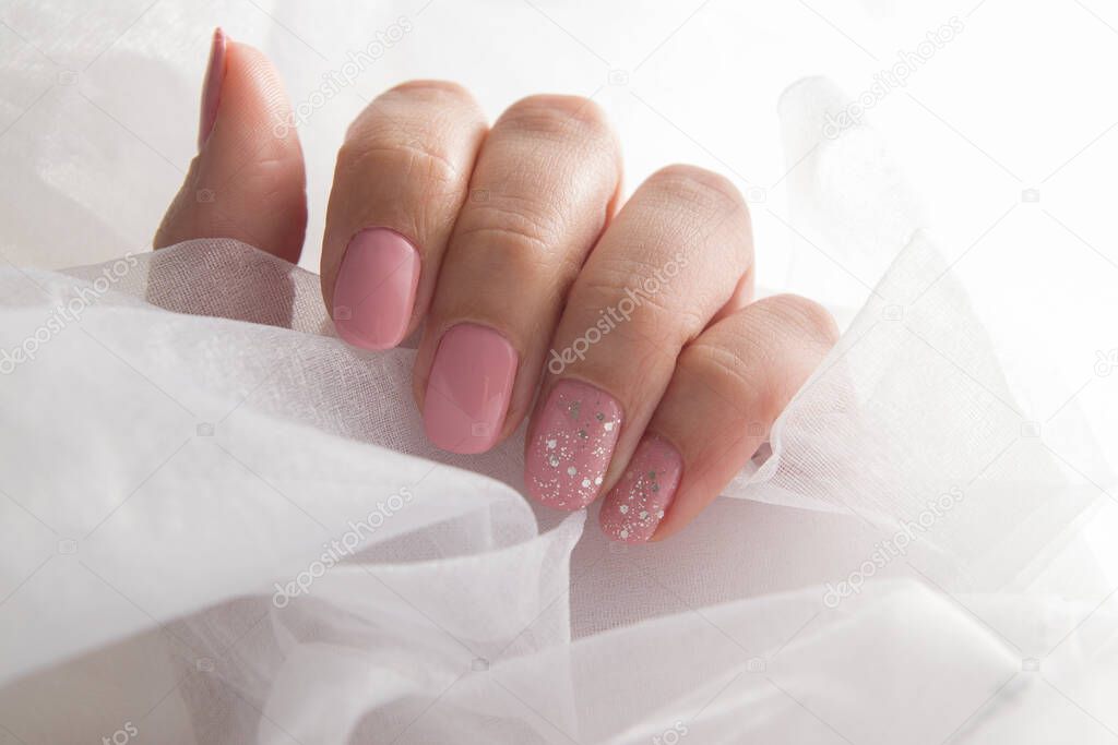 Soft pink varnish and sparkles on nails - gel varnish salon coating manicure.