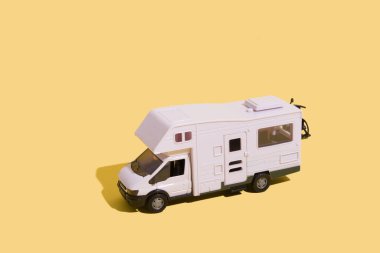 Toy van on a yellow background. Minimalistic summer family vacation concept