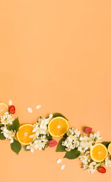 Citrus and strawberry slices with garden jasmine flowers on an orange background. Summer background for stories