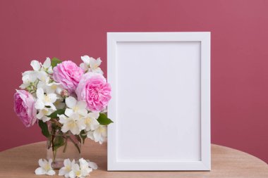 Boş beyaz çerçeve pembe arka plandaki çiçeklerle uyumlu. Metin veya resim için şablon