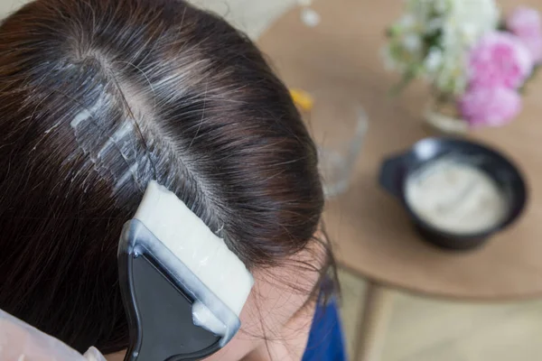 Saçlarının üstünde gri saçlı boya fırçası. Gri saç boyama konsepti