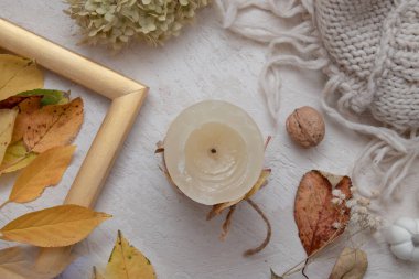 Sonbahar mahsulü, yaprakları dökülmüş, kuru gül, mumlar ve örülmüş battaniyeli üst yaşam manzarası. Sonbahar atmosferi kavramı