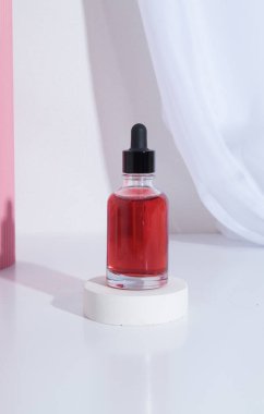 Kırmızı kozmetik sıvısı ya da podyumda yağlı pipetli cam damlası şişesi.