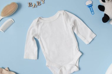 Çocuk kıyafetleri üst görünümü, beyaz bebek tulumu mavi arka planda. Metin veya logo yeriniz