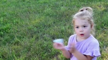 Şirin küçük kız. 3 yaşında, kıvırcık saçlı. Yeşil doğal bir arka planda at kuyruğu takmış.