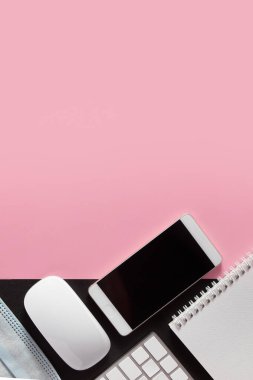 Düz bir masaüstü bilgisayarı, klavyesi, telefonu, tıbbi maskesi vardı. Renkli arka planda kopyalama alanı olan bir not defteri vardı. Dikey format. Çevrimiçi eğitim, iş, iş konsepti