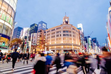 Tokyo, Japonya - 10 Aralık 2015: İnsanlar Tokyo 'daki Ginza alışveriş bölgesinin kalbinde acele ediyorlar. İkonik Ginza Wako binası arka tarafta.