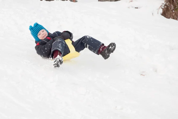 Cheerful child goes from the snow slides — Stock Photo, Image